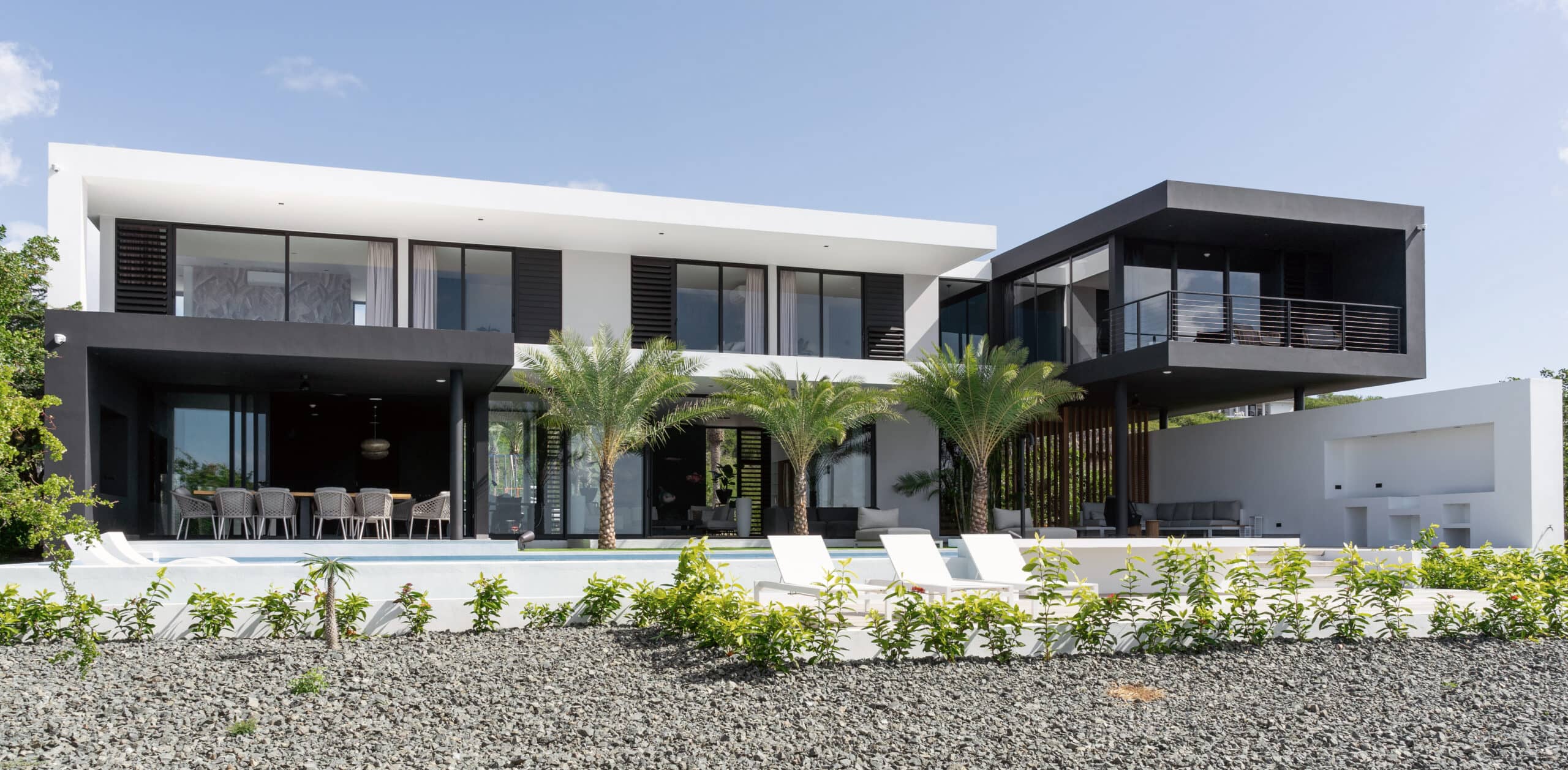 Moderne Black Box Villa met zwarte gevelaccenten, grote glazen schuifpuien, witte stucafwerking en panoramisch uitzicht op tropisch landschap en zee, ontworpen door STATE of Architecture.
