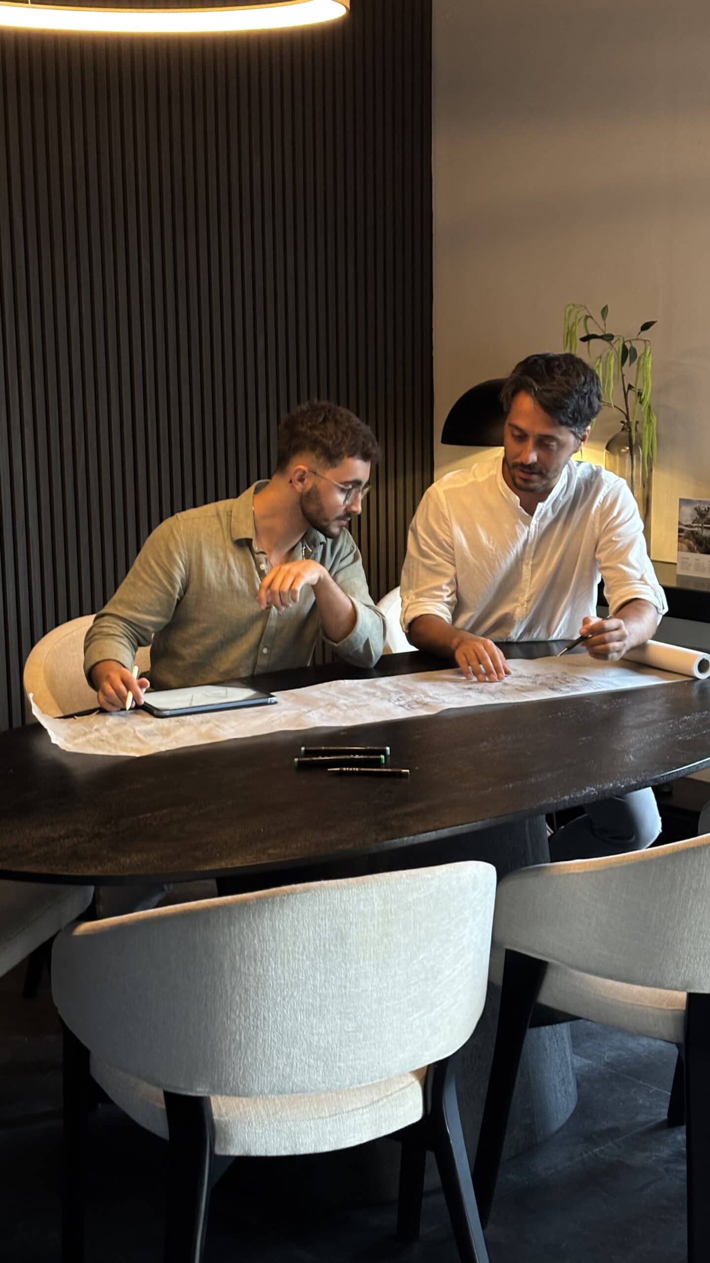 Twee mensen in overleg over het ontwerp en de kosten van een prefab villa bij STATE of Architecture.