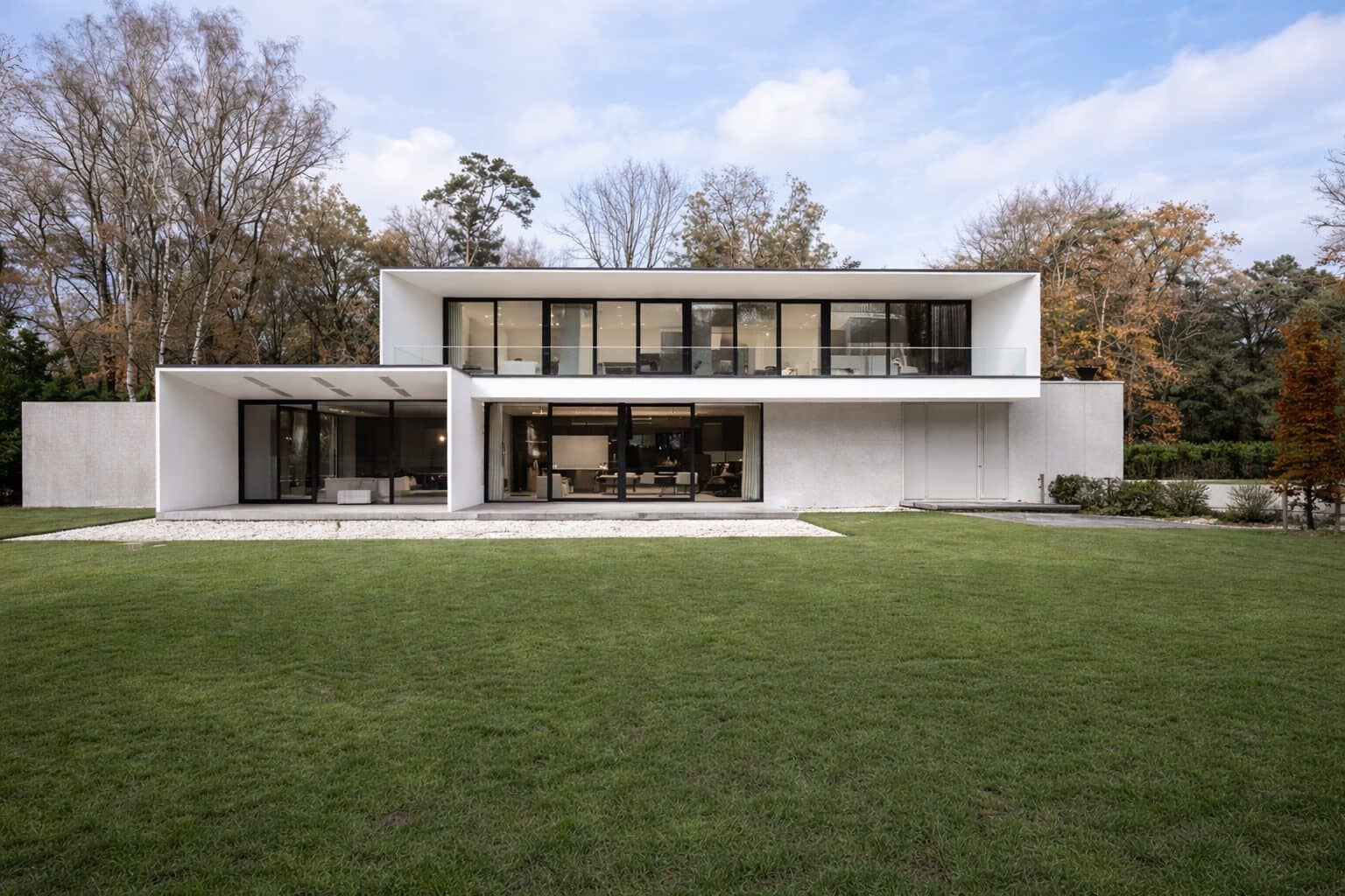 Villa met strakke lijnen tuin helder transparant glas wit beton
