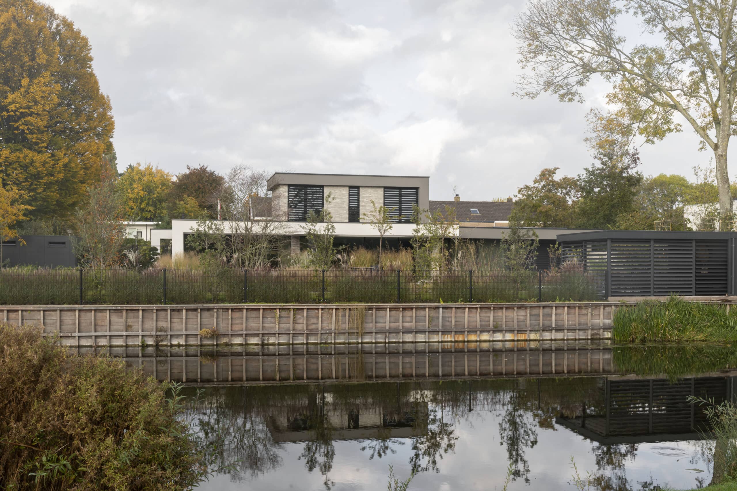 Villa achter een kanaal met bossen groen en beton