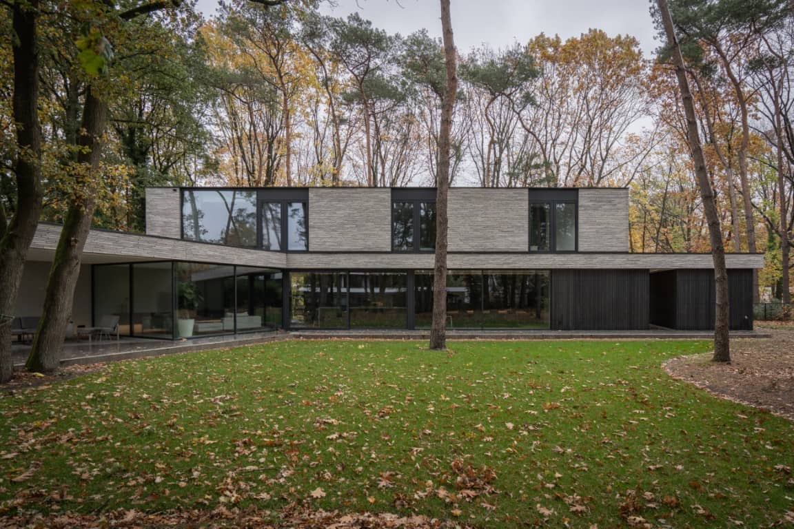 Hedendaagse villa met horizontale gevelbekleding, royale glasvlakken en een groene bosomgeving.